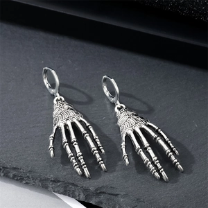 Gothic punk skeleton hand earrings in vintage silver metal with a minimalist dark background