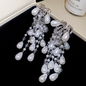 Macro shot of silver tassel earrings with teardrop pearls on a black velvet box