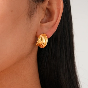 Close-up of model wearing gold-plated C-shaped geometric spiral earrings in a minimal style