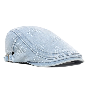 Detail of light blue denim newsboy cap with white embroidery dots and metal buckle