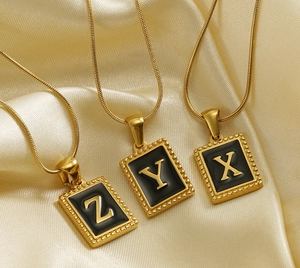 Detail shot of golden snake chains with square black enamel alphabet pendants X Y Z