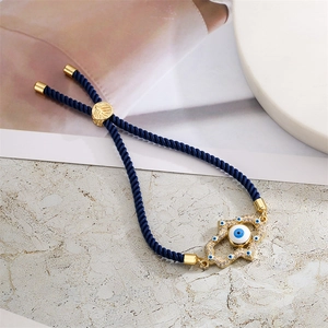 Detail of Hamsa hand and Evil Eye charm with blue woven cord and golden metal closure