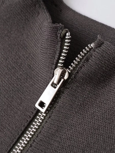 Macro view of silver metal zipper detail on dark gray knitted jacket with fine texture