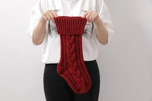 Large red cable-knit Christmas stocking being held by hands to show its size and texture