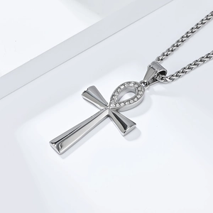 Silver Ankh cross pendant with crystals on wheat chain over white geometric background