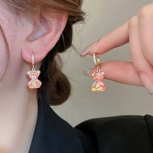 Gros plan de boucles d'oreilles ours rose irisé avec anneau doré et pierres en zircon