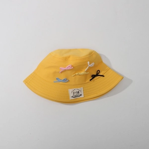 Detailed shot of yellow sun hat featuring five colorful 3D bows and woven brand label