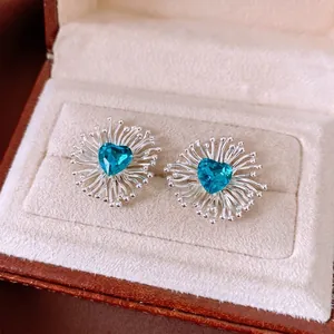 Elegant silver hollow flower stud earrings featuring blue heart-shaped zirconia stones.