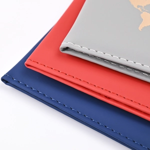 Detailed view of PU leather passport covers in navy blue, red, and grey with gold map design