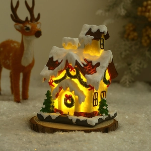 Close-up of glowing Christmas miniature snow house with festive tree and snowy roof detail