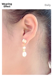 Macro detail of elegant double baroque pearl earrings with golden metal links on a model