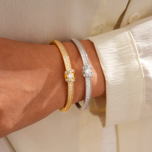 Detail of 18K gold and silver oval clasp bracelets with pavé diamonds on a wrist