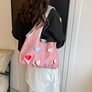 Sac seau en similicuir rose avec écussons cœur colorés porté à l'épaule par un mannequin