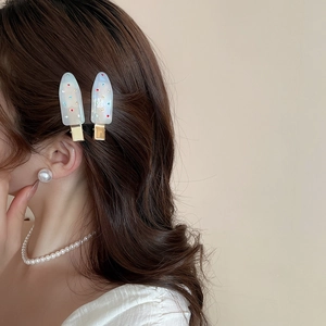 Detail of two acrylic hair clips with colorful crystals worn on brunette wavy hair