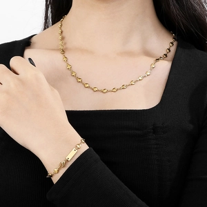 Golden heart-shaped chain necklace and bracelet with rectangle tag worn by model
