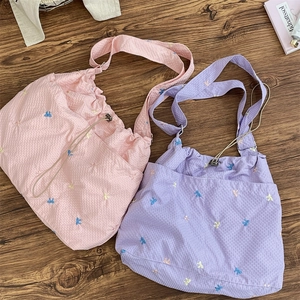 Close-up of pink and purple seersucker shoulder bags with colorful bow embroidery details