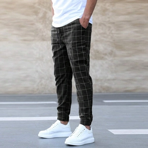 Detail shot of men's dark green plaid pants with drawstring waist and jogger cuffs