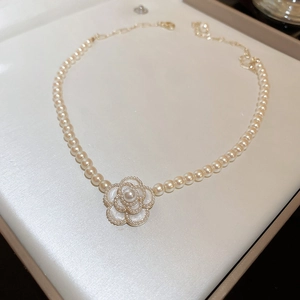 Close-up of vintage pearl necklace with golden camellia pendant in beige gift box