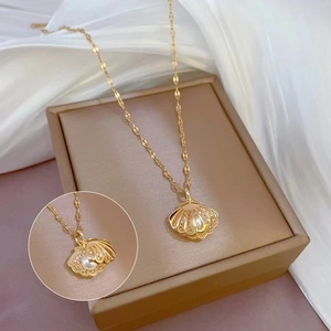 Elegant gold hollow shell pendant necklace with pearl on brown jewelry box surface