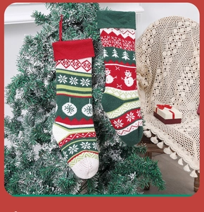 Festive knitted Christmas stockings with snowman and snowflake patterns on a snowy tree