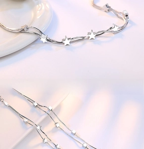 Detail of silver double-layered snake chain bracelet with star and square pendants