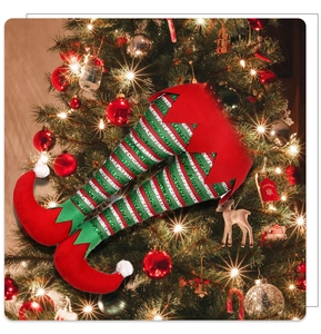 Close-up of sparkling sequined elf legs decoration nestled in a lush Christmas tree branch