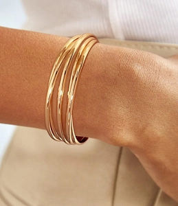 Close-up of elegant multilayer gold cuff bracelet with high-polish metallic texture