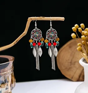 Detail of bohemian tassel earrings with enamel discs and silver leaf charms on a branch