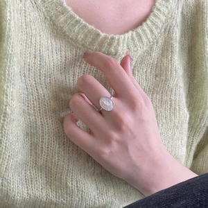 Detail of 925 sterling silver Maria shell ring worn against a green knit sweater