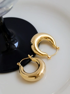 Close-up of golden chunky hoop earrings with a high-polished finish on a display tray