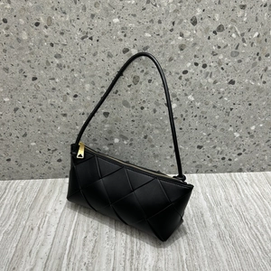 Close-up of black woven leather texture and iconic gold triangular zipper detail