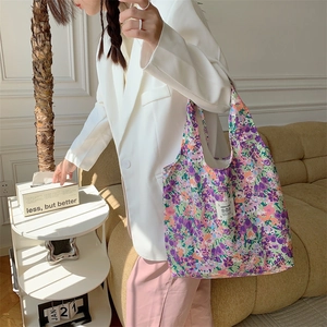 Dettaglio di una borsa tote in tela a fiori viola indossata da una modella in interni eleganti