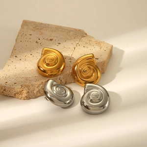 Dettaglio di orecchini a spirale in oro e argento appoggiati su pietra naturale