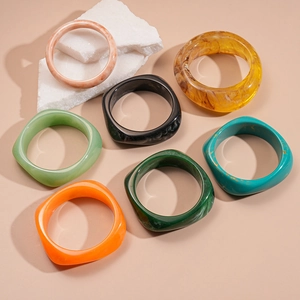 Minimalist geometric resin bracelets in orange and amber colors on marble background