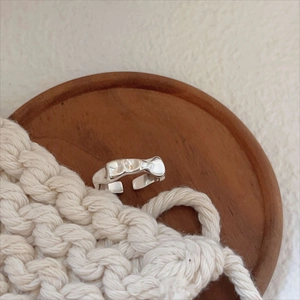 Artistic 925 sterling silver irregular open ring on wooden tray with cozy knit background