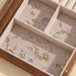 Detail of DIY 18K gold and silver metal alphabet pendants in a wooden jewelry box