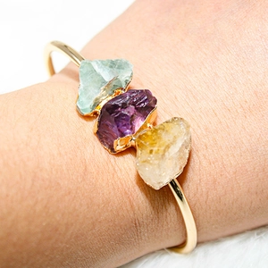 Macro detail of natural amethyst and citrine stones on a gold adjustable bangle
