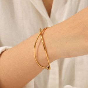 Minimalist 18k gold plated stainless steel crossover open bangle worn on model wrist