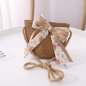 Detailed view of kids' straw bag with large floral bow and twisted cord shoulder strap