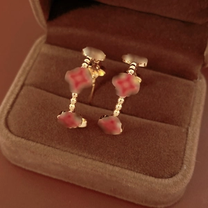 Macro detail of gold-plated clover earrings with red agate inlays in a jewelry box