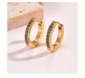 Detail of gold huggie earrings with a vertical row of multi-colored crystals