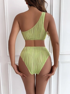 Detail of lime green textured one-shoulder bikini back view on white wood paneling
