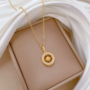 Macro shot of gold compass necklace pendant with sparkling crystals on silk fabric