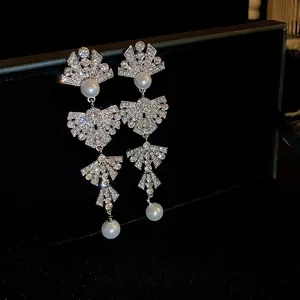Silver bow pearl tassel earrings with rhinestones on a black velvet background