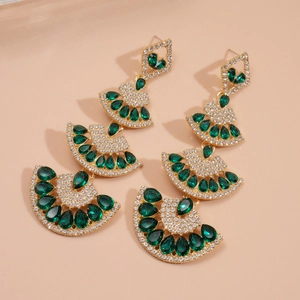 Close-up of tiered fan-shaped earrings with emerald green crystals and gold finish