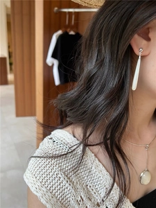 Close-up of elegant teardrop mother of pearl earrings worn by a model in soft natural light