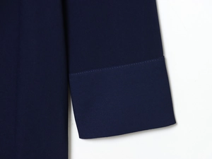 Gros plan détaillé des poignets de la robe bleu foncé avec coutures et texture tissée