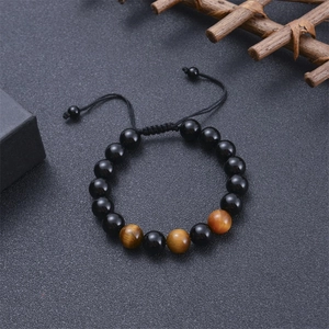 Detail of 10mm tiger eye and lava stone adjustable beaded bracelet on textured surface