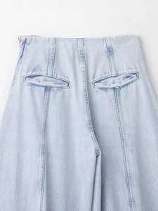 Detail van een lichtblauwe spijkerbroek met hoge taille, zijrits en stiksel op de achterzak
