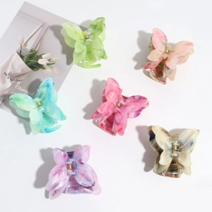 Detailed close-up of marble-patterned butterfly hair claws in six vibrant gradient colors